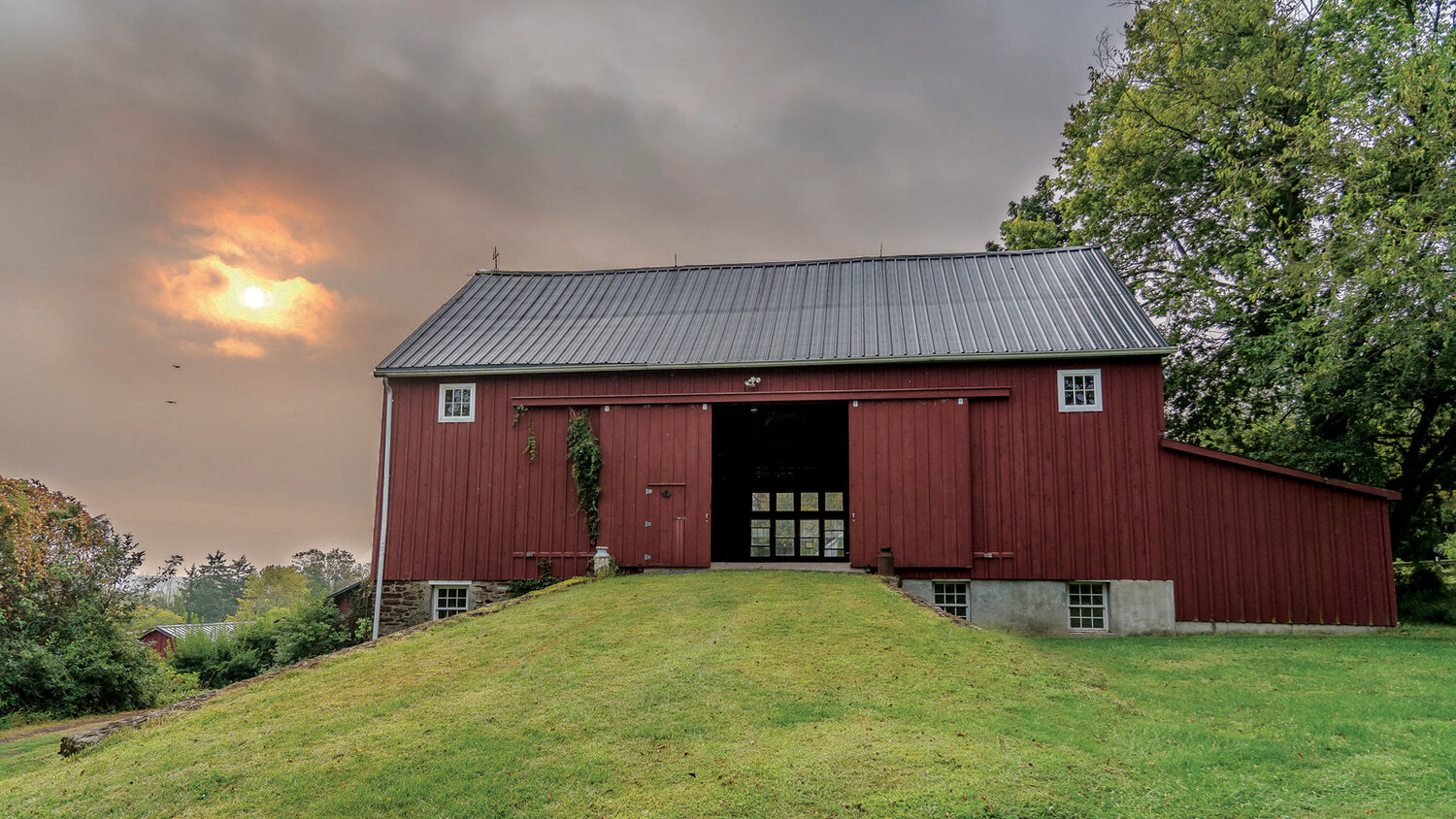 Rising Sun Farm, a modified example of a Pennsylvania barn from the mid-nineteenth century, provides a spectacular sunset view from its open barn doors.