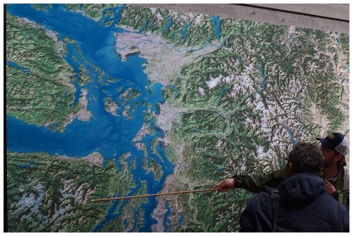 Christian points out the Olympic Peninsula on a satellite image of northwest Washington, which graces an exterior wall of the NCI Environmental Learning Center