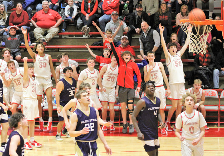 Lancer senior Andrew Eichmeier (21) stares down one of his two three-point bombs Friday night as his Lancer teammates erupt on the sidelines. Eichmeier came off the bench to score eight points in North Scott's 72-44 rout of Muscatine.