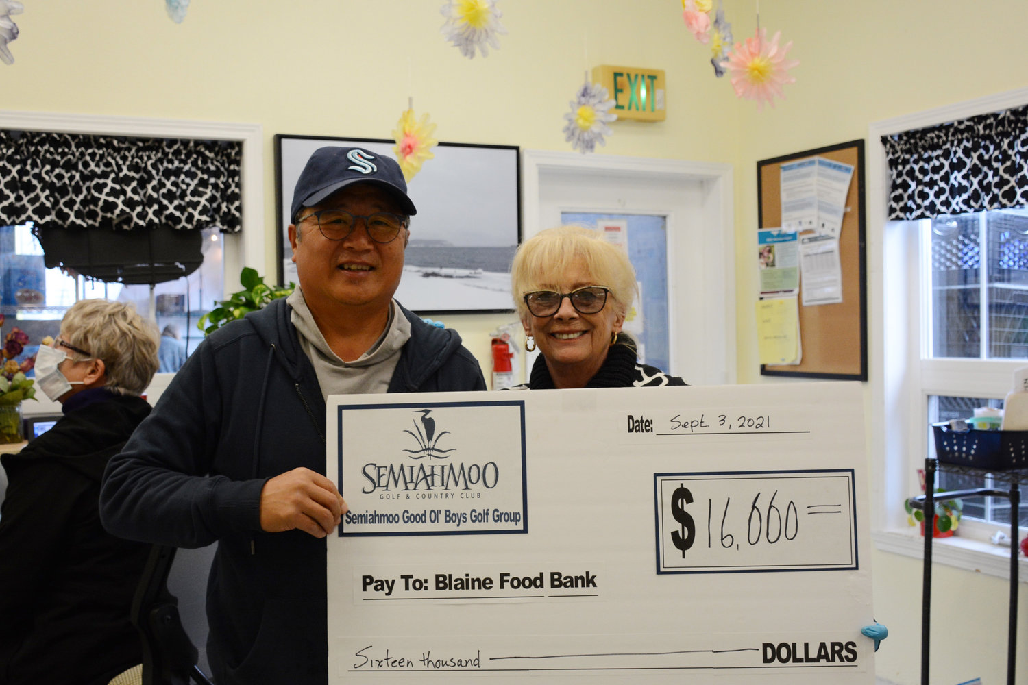 Thomas Yang of the Semiahmoo Good Ol’ Boys golf group hands Blaine Food Bank operations manager Sally Church a check for $16,000 on September 3, 2021.