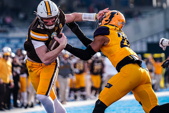 Wyoming quarterback Levi Williams stiff-arms a Kent State defender during the Famous Idaho Potato Bowl on Tuesday in Boise, Idaho. Williams finished with 200 yards rushing and four touchdowns on the ground and one passing touchdown.
