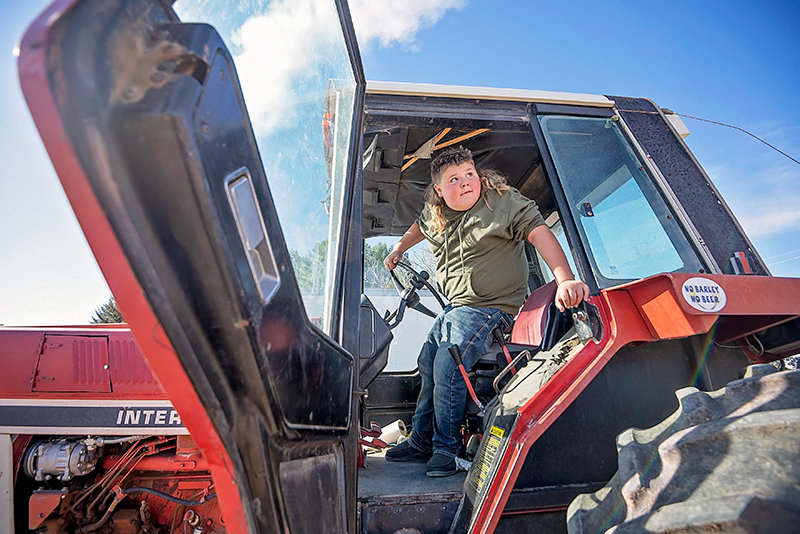 Tag Thompson steps out of his tractor after starting it earlier this month at Thompson Farms. Thompson saved money to purchase his own tractor, reaching a goal of buying one before he turned 12.