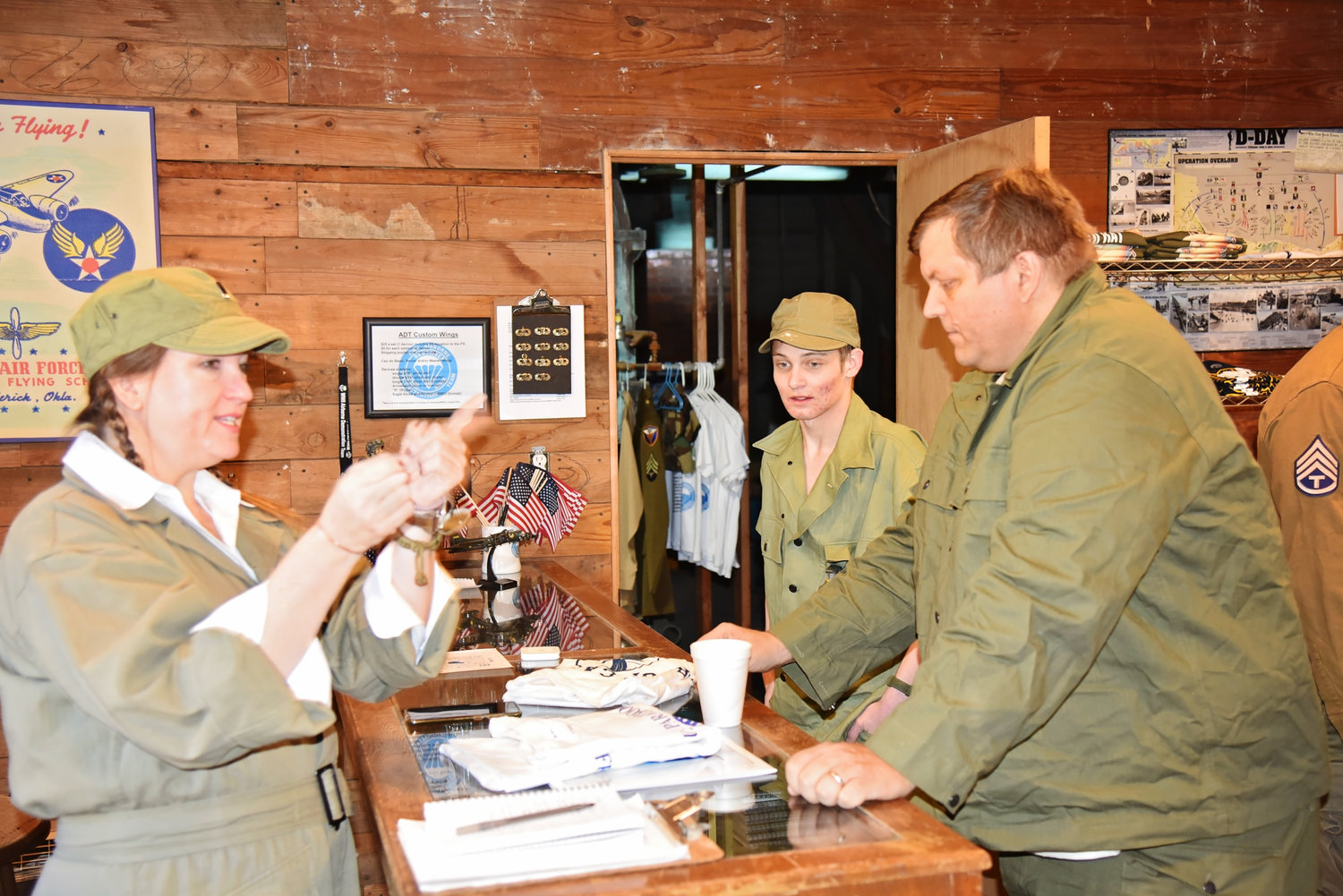 WWII Airborne Demonstration Team member Laura Goodwin makes a sale at the PX (gift shop) to visitors Carter Cavicchio from Oklahoma City (left) and Dustin Roderigas (right) from Lawton.
