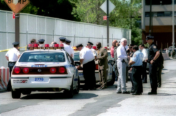 Police officers and school officials survey the site where a JFK student was stabbed to death by a classmate on the way to summer school in 2002. It wasn’t until four years after the incident that Kennedy was put on a list of Impact Schools and given special scrutiny.