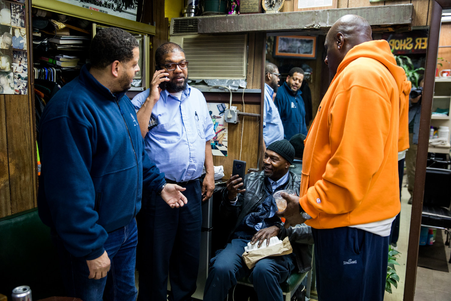 Walter Watson, second from left, talks on the phone inside Marble Hill’s International Unisex Salon on March 6, where he was a longtime customer. The MTA bus driver would die from complications related to COVID-19 less than two months later at 55.