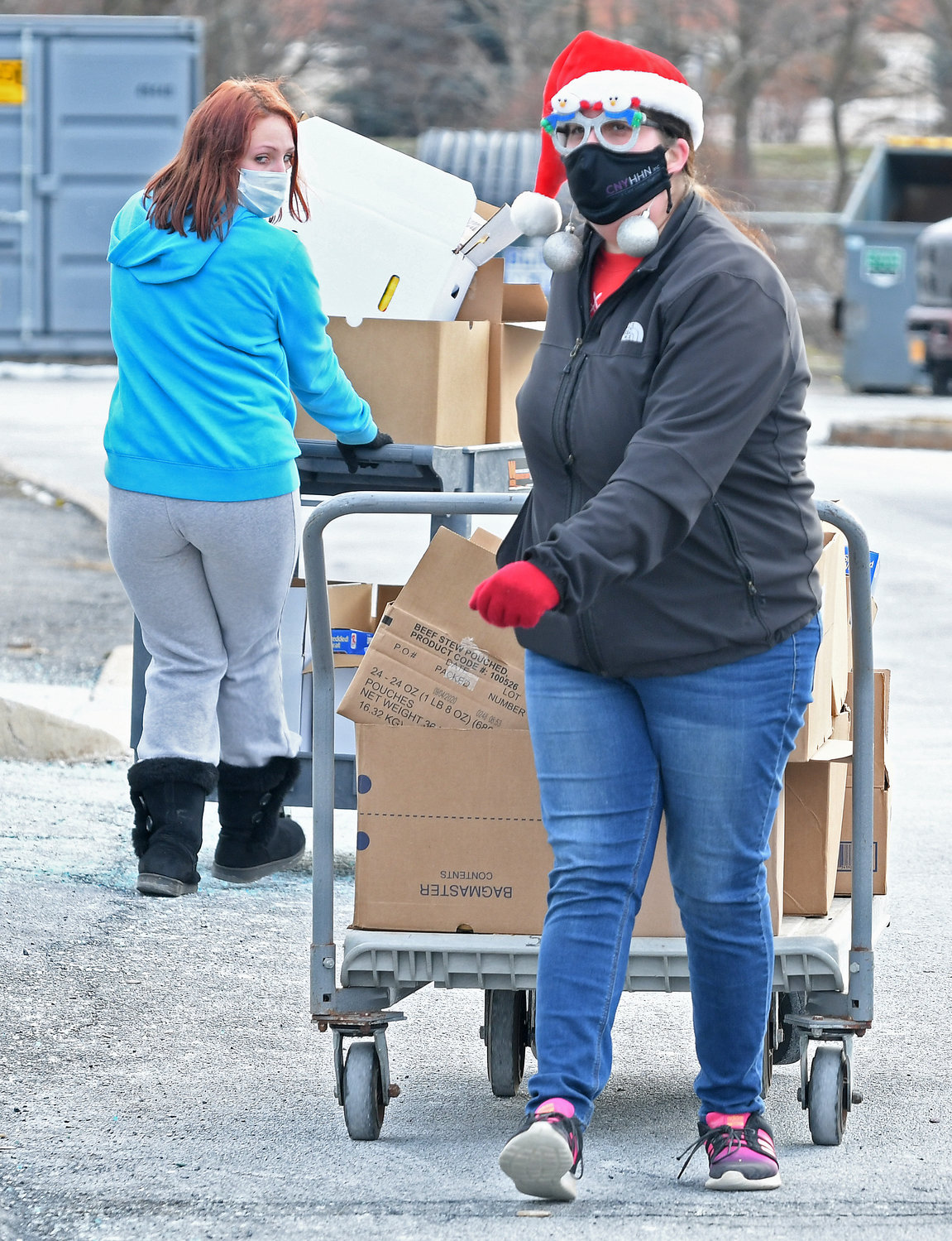 CARTING OUT THE FOOD — Rolling out carts filled with food items for a Connected Community Schools Holiday Food Giveaway on Wednesday at Staley Elementary School are, from left, Mandi McGuigan and Alyssa Whitaker. The food distribution program marked one million pounds of food that has been provided since last March in response to COVID-19.