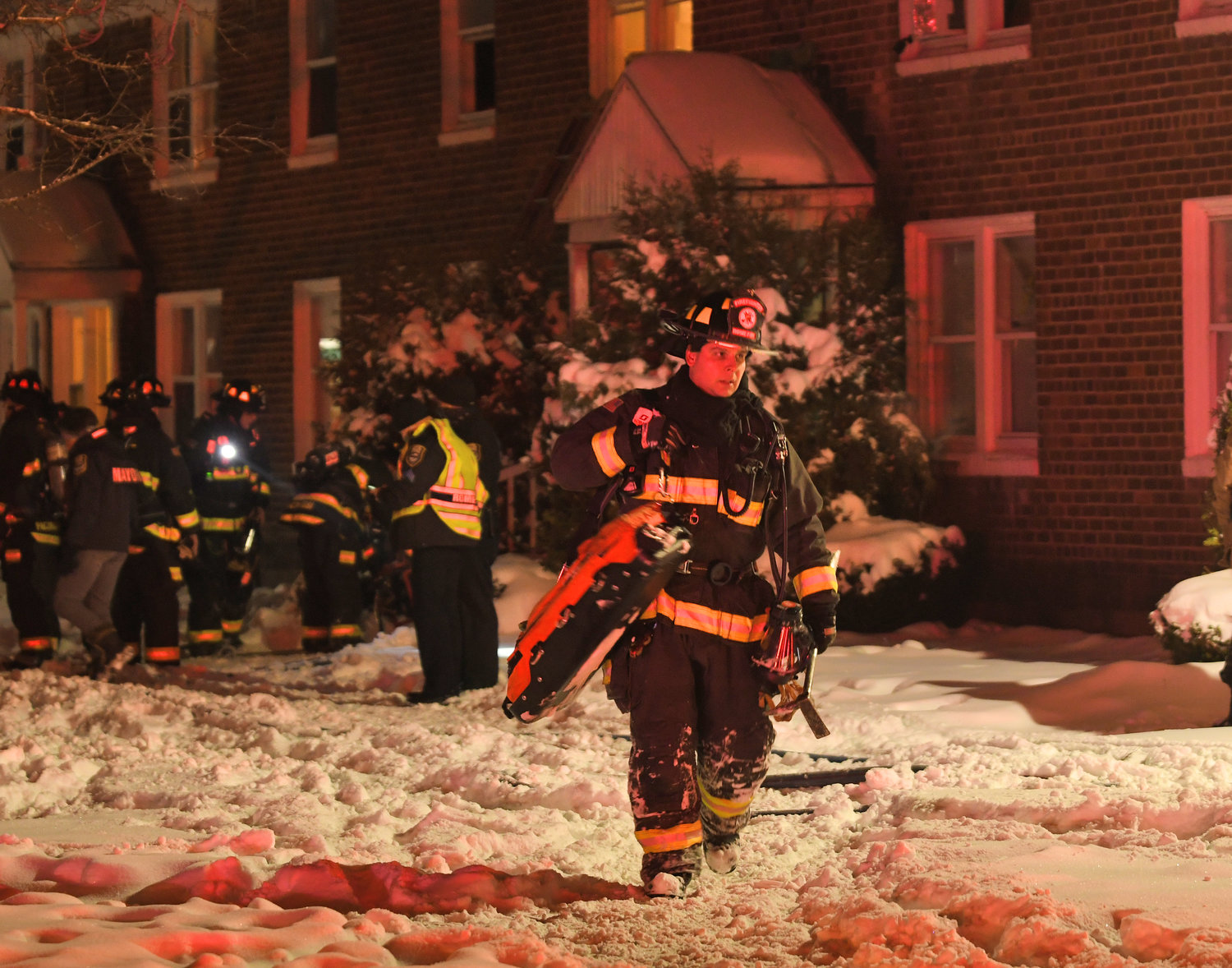 HEADING BACK — Firefighter Joe Fusco brings equipment back from the scene of a fire at an apartment complex on East Bloomfield Street to his rig on Sunday night. One man was treated for smoke inhalation. The fire was contained to one apartment, however some other apartments in the building suffered smoke damage.