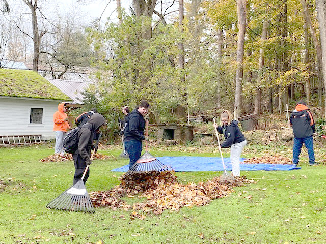 HELPING OTHERS — Members of the Remsen High School Class of 2022 and the National Honor Society participated in a community fall cleanup project in the village late last month. Here, students rake up leaves for an elderly member of the community.
