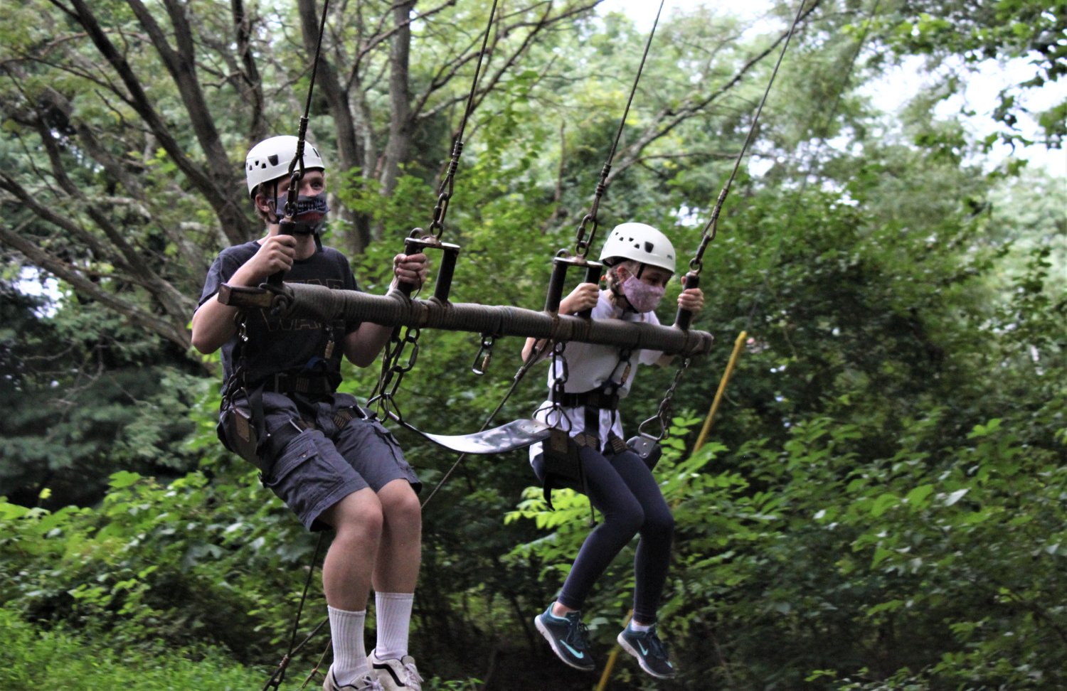 From left, Jeremiah Faust and Lillian Cross rode in a swing that flew high into the tree canopy during Camp Phoenix Teen Grief Camp held at Terrapin Adventures in Savage, Maryland.